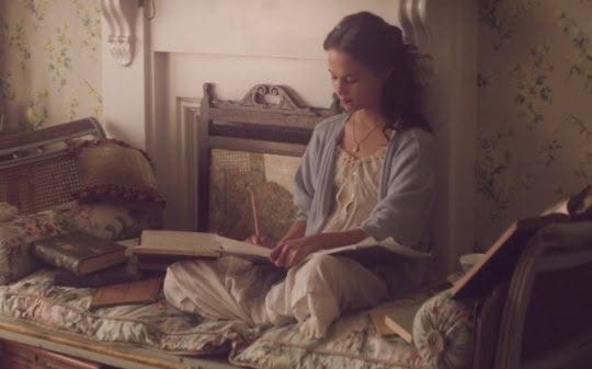 This may contain: a woman sitting on top of a bed reading a book