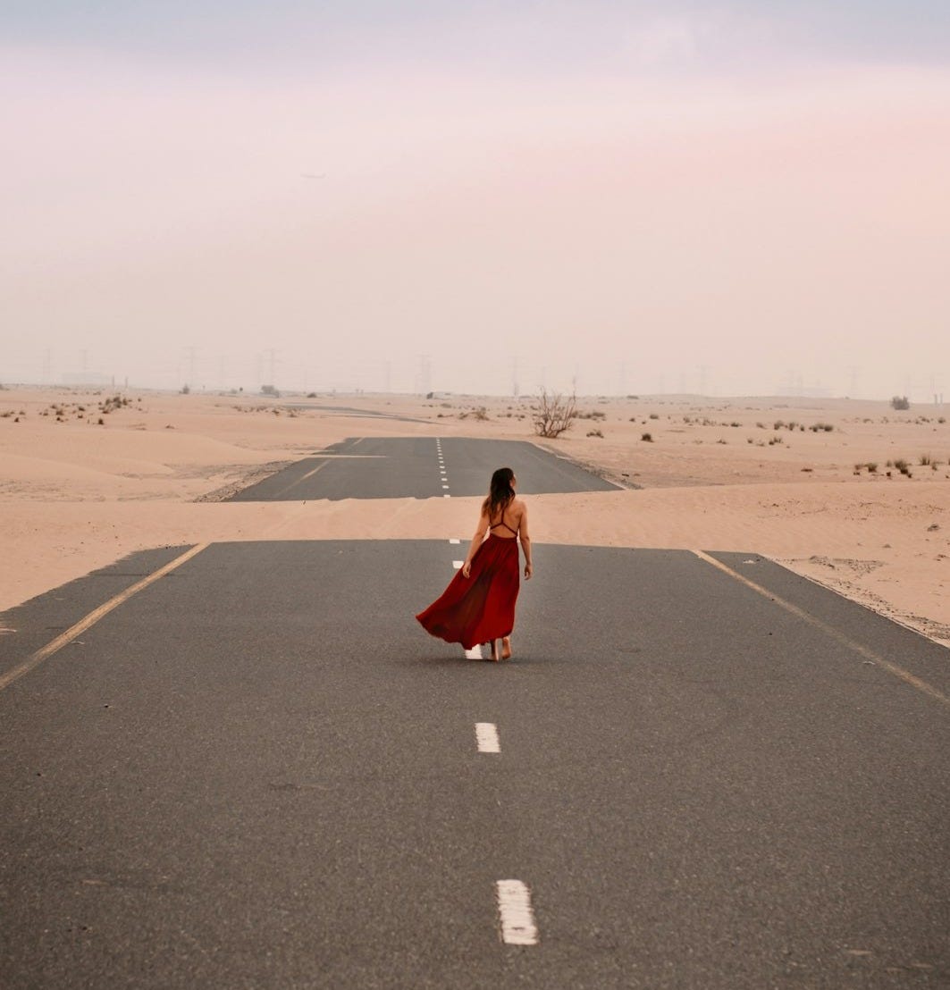 a woman in a red dress is walking down the road a woman in a red dress is walking down the road