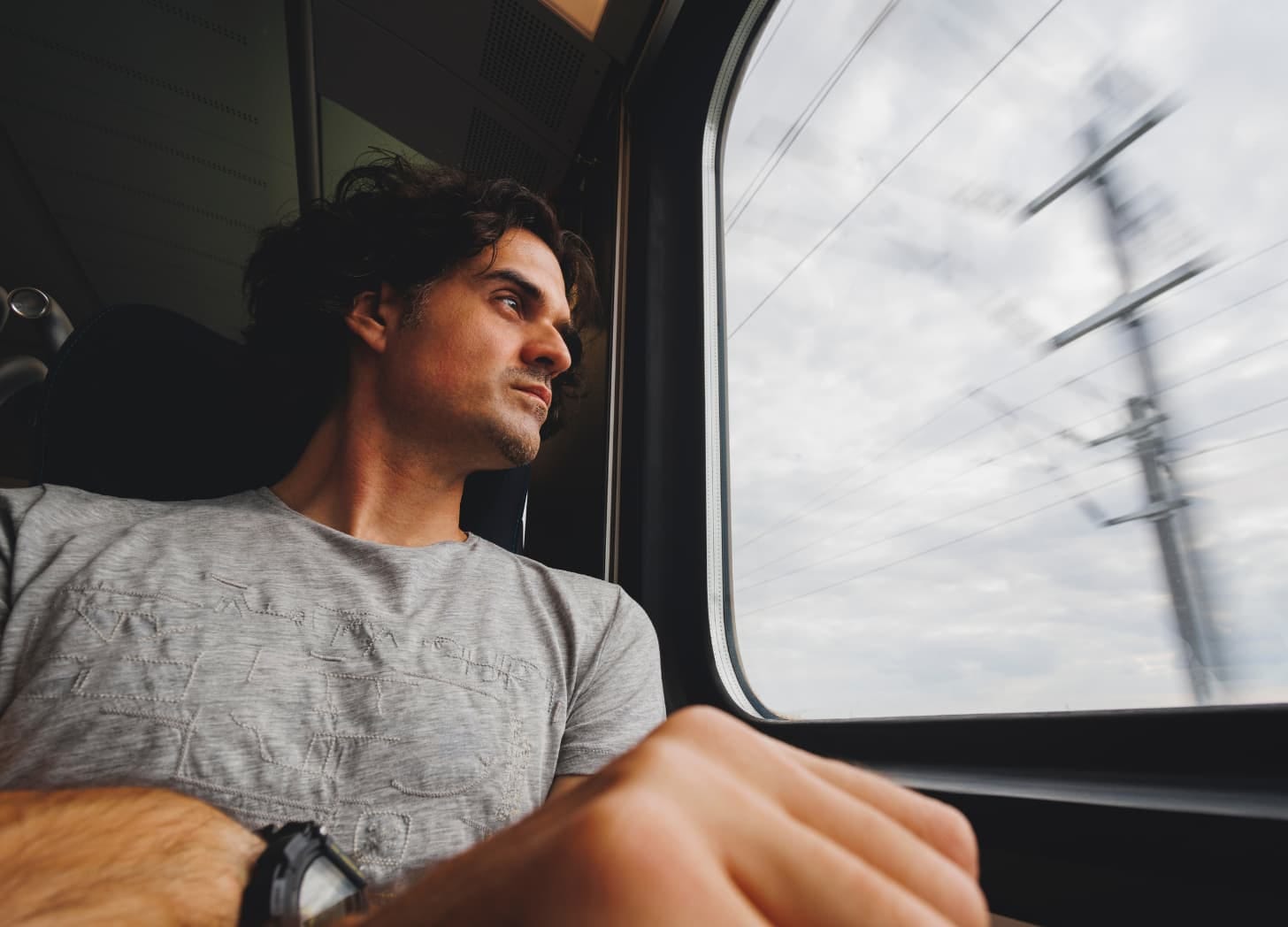 A man with dark hair looking out the train window. A man with dark hair looking out the train window.