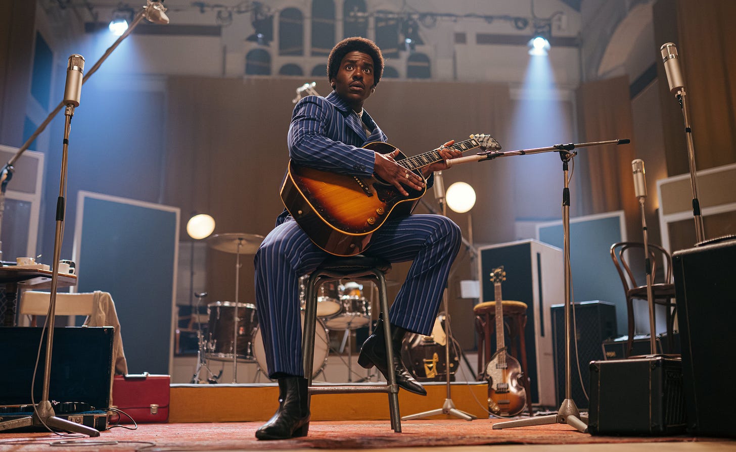 Ncuti Gatwa looking dapper as the Doctor holding a guitar in a publicity photo from The Devil's Chord