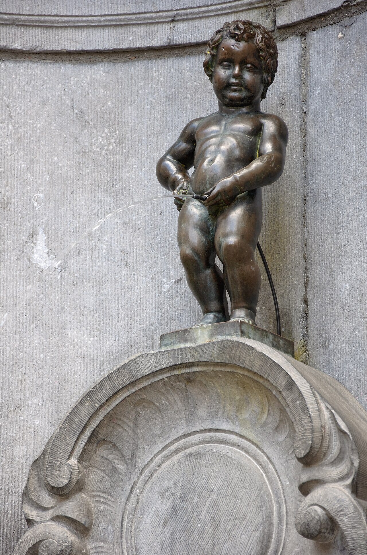 Manneken Pis, a small bronze boy fountain in a stone niche in Brussels Manneken Pis, a small bronze boy fountain in a stone niche in Brussels