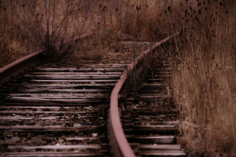a close-up of a train track surrounded by dried grass a close-up of a train track surrounded by dried grass