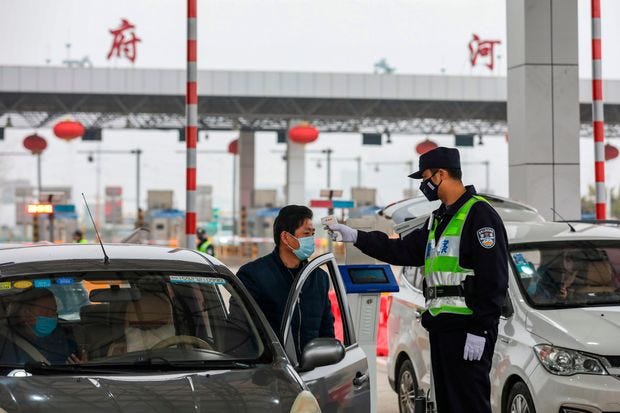A police officer checks the temperature of a driver in Wuhan on Jan. 24.