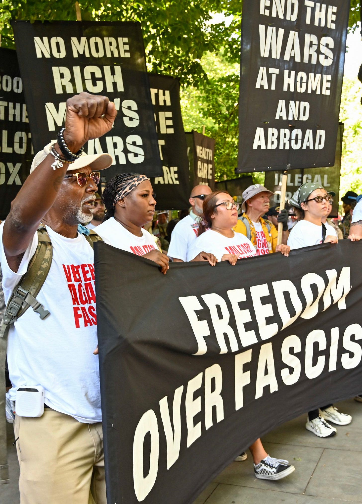 Una pancarta de protesta con el texto "NO MORE RICH WARS AT HOME AND ABROAD" (No más guerras de ricos en casa y en el extranjero) en la parte superior. La sección central dice "FREEDOM OVER FASCISM" (Libertad sobre el fascismo) y "END THE WARS AT HOME AND ABROAD" (Terminar con las guerras en casa y en el extranjero). Una pancarta de protesta con el texto "NO MORE RICH WARS AT HOME AND ABROAD" (No más guerras de ricos en casa y en el extranjero) en la parte superior. La sección central dice "FREEDOM OVER FASCISM" (Libertad sobre el fascismo) y "END THE WARS AT HOME AND ABROAD" (Terminar con las guerras en casa y en el extranjero).