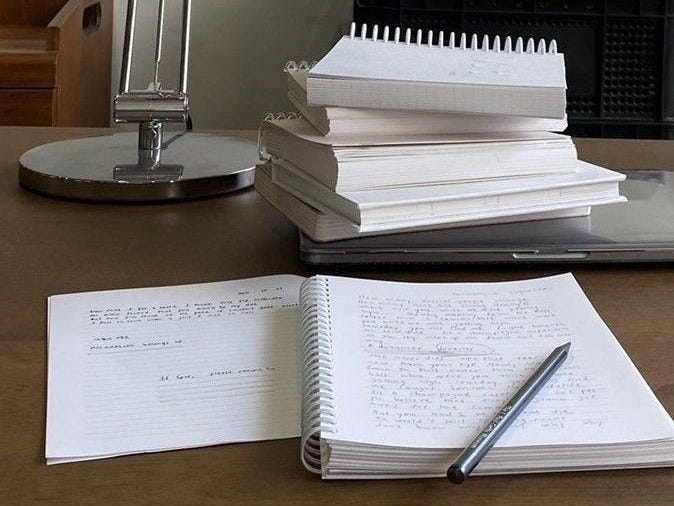 This may contain: a stack of books sitting on top of a table next to a lamp and radio