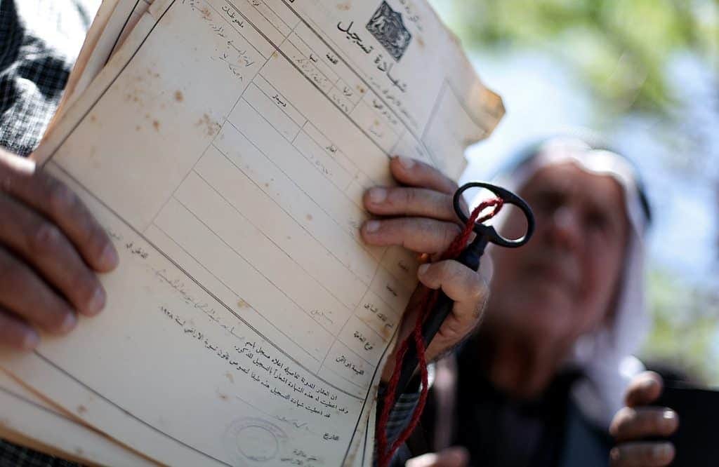 A Palestinian man shows deeds to his land during a rally marking the Nakba in Gaza City, on May 15, 2013. (Photo: Ali Jadallah / APA Images)