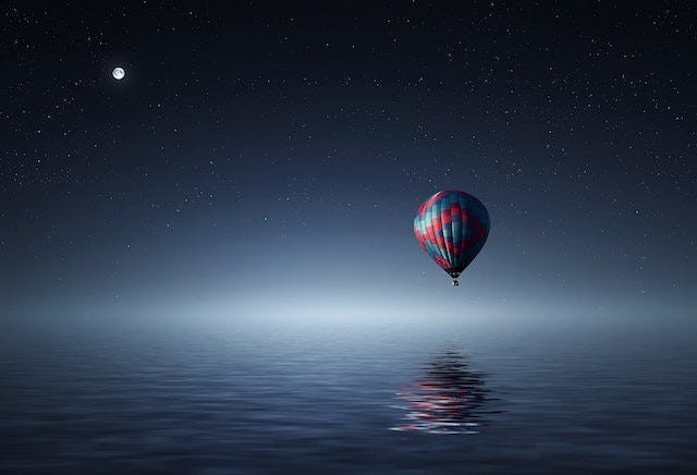 a hot air balloon floating over the ocean at night