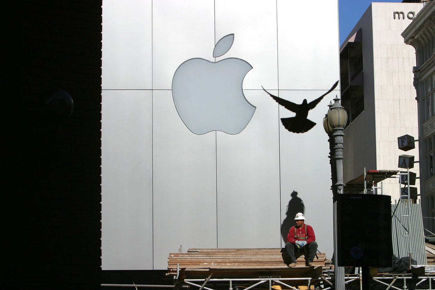 A worker sits on scaffolding outside The Apple Store, San Francisco. A silhouette of a flying bird is in the foreground. A worker sits on scaffolding outside The Apple Store, San Francisco. A silhouette of a flying bird is in the foreground.