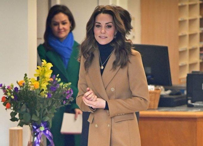 Princess Kate wearing brown coat with Emily Nash standing in the background