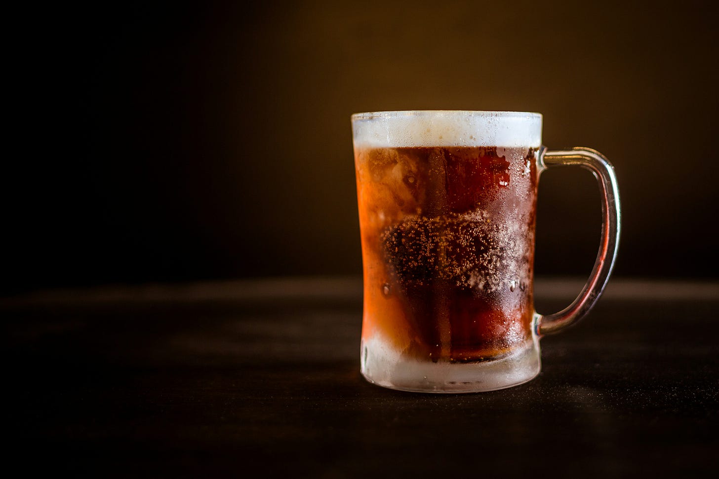 brown beer sits in a cold, frostry mug on top of a table brown beer sits in a cold, frostry mug on top of a table