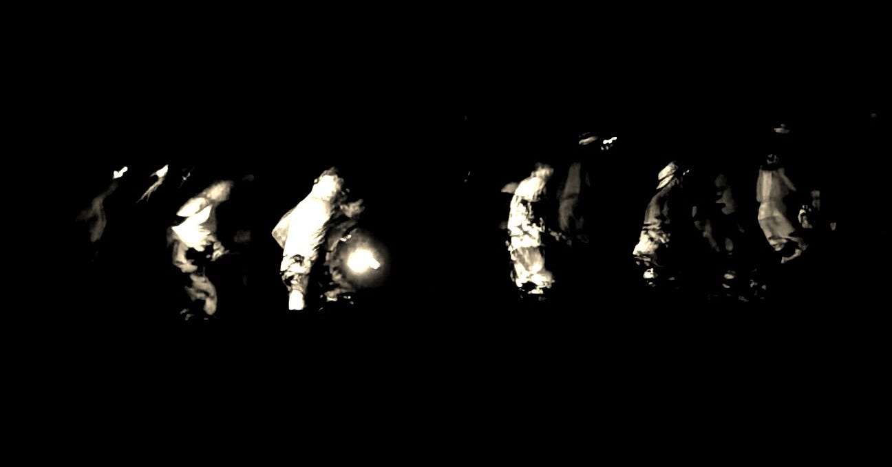 Photo of runners in the dark moving with headlamps.