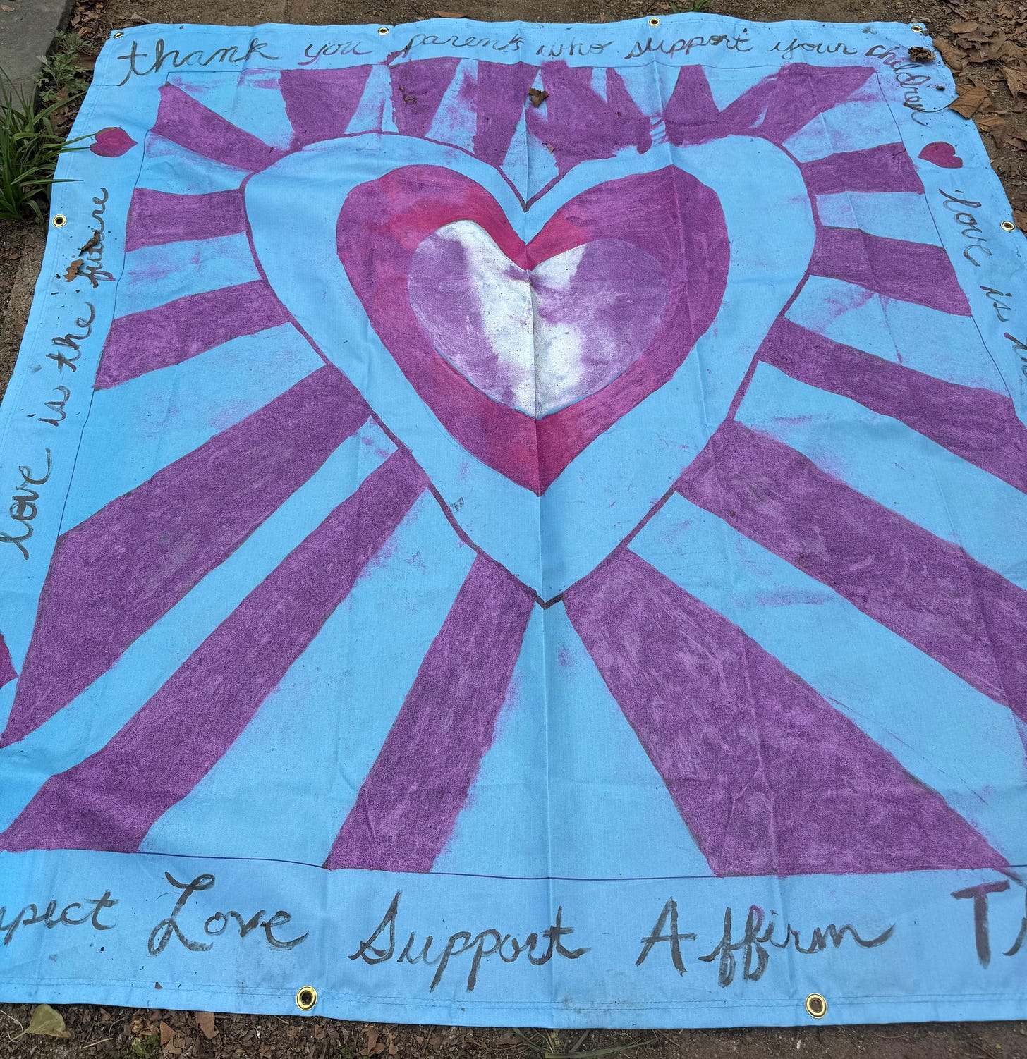 Quilt panel for ACLU monument of hearts in trans flag colors with radiating lines, border text says thank you parents who support your children, love is the future, protect love affirm support