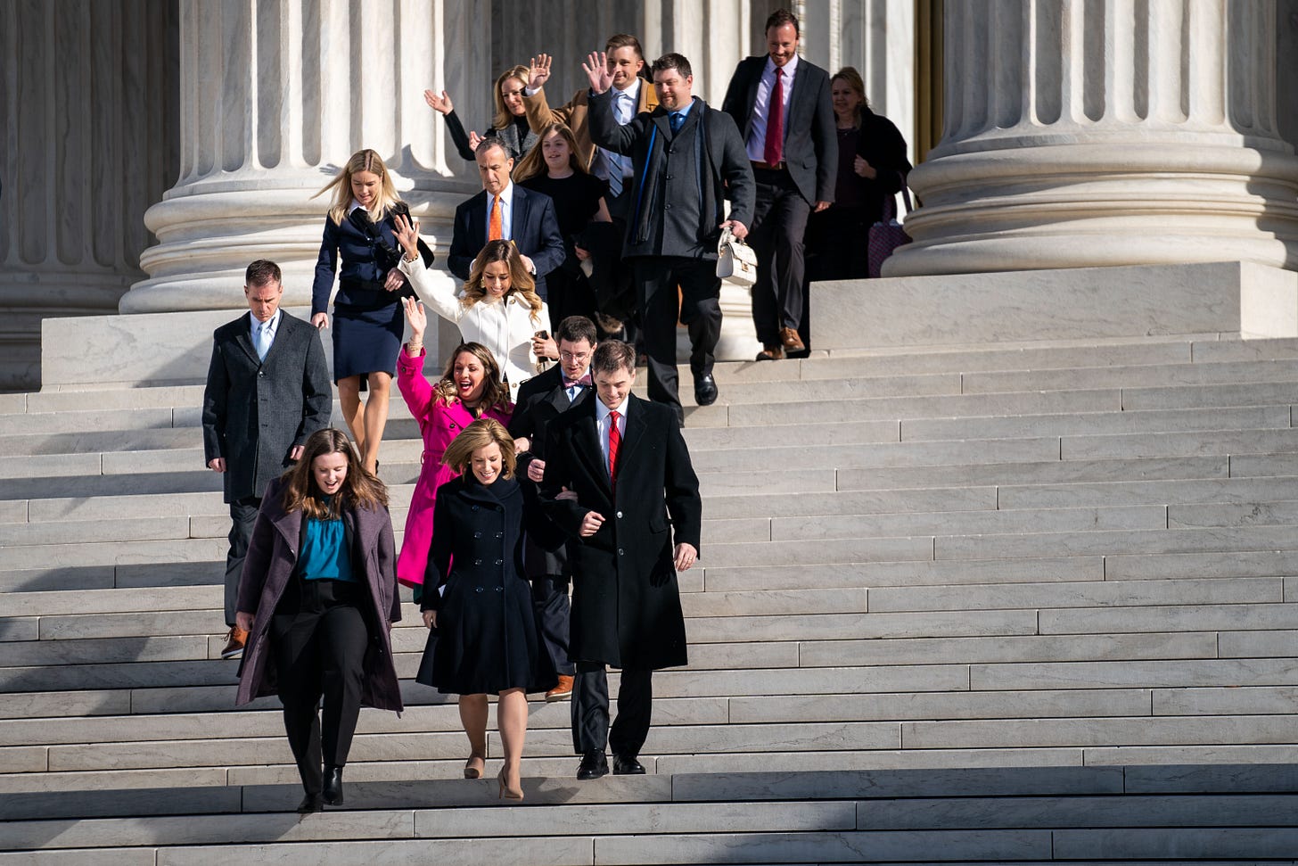 Lorie Smith (center in pink) and others leave Supreme Court after oral arguments, December 2022. Lorie Smith (center in pink) and others leave Supreme Court after oral arguments, December 2022.