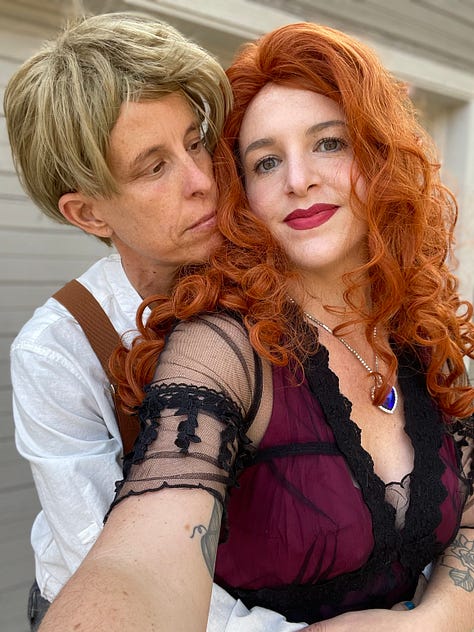 Megan Falley wears a curly red wig and maroon gown, Andrea Gibson wears a short blond wig, linen shirt and suspenders. They become Jack and Rose from Titanic, for a moment.