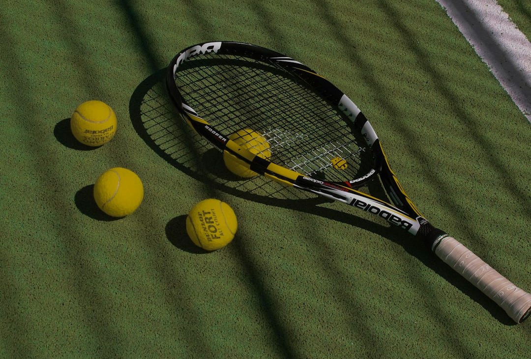 a tennis racket and four tennis balls on a court