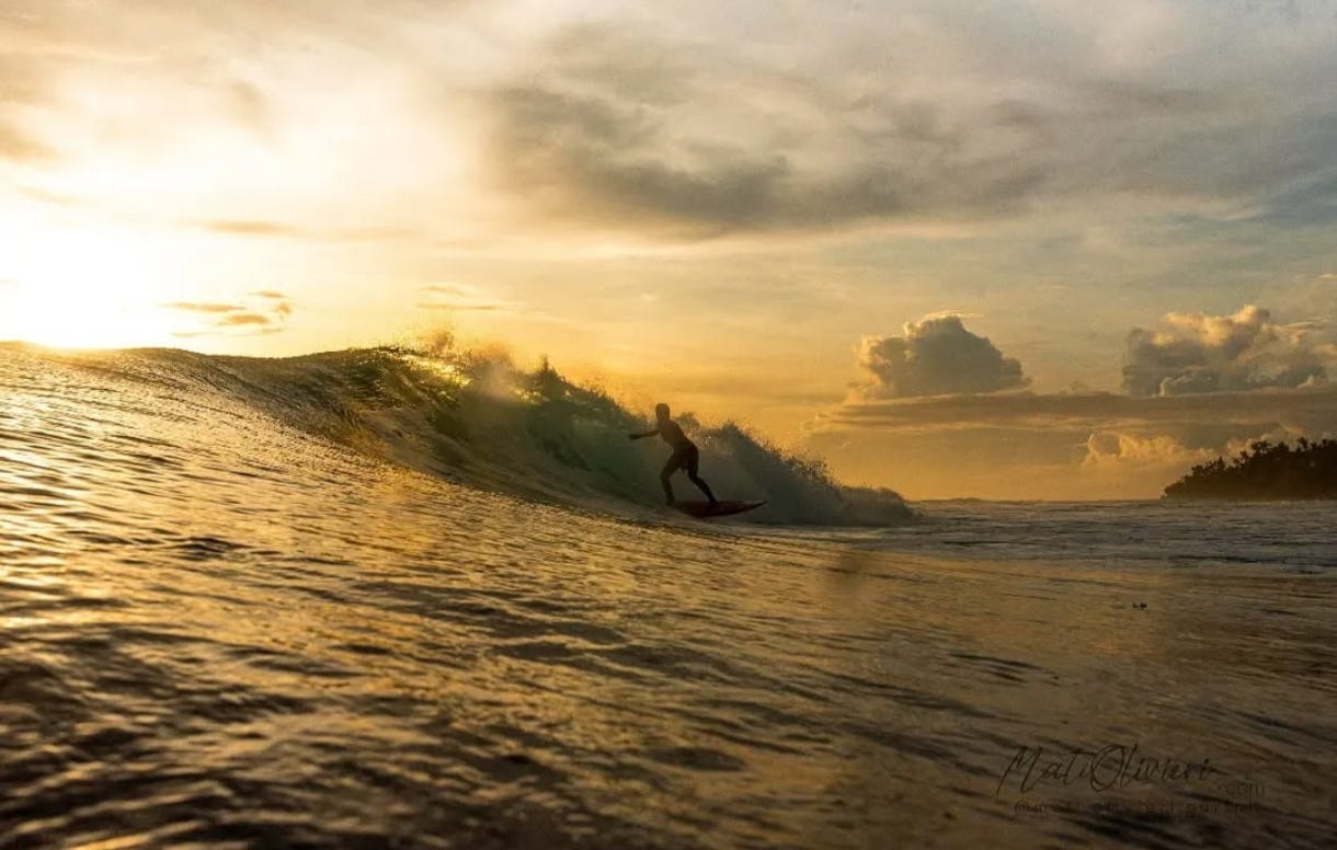Silhouette of Astrid Sadaya surfing a wave tinted gold by the sun low on the horizon. Astrid is a surfer, global food explorer, former pro rugby player, and now our first featured AMP⚡️ Meal Prep guest contributor. Astrid brings a bold, adventurous spirit to her world travels, cooking, and writing.