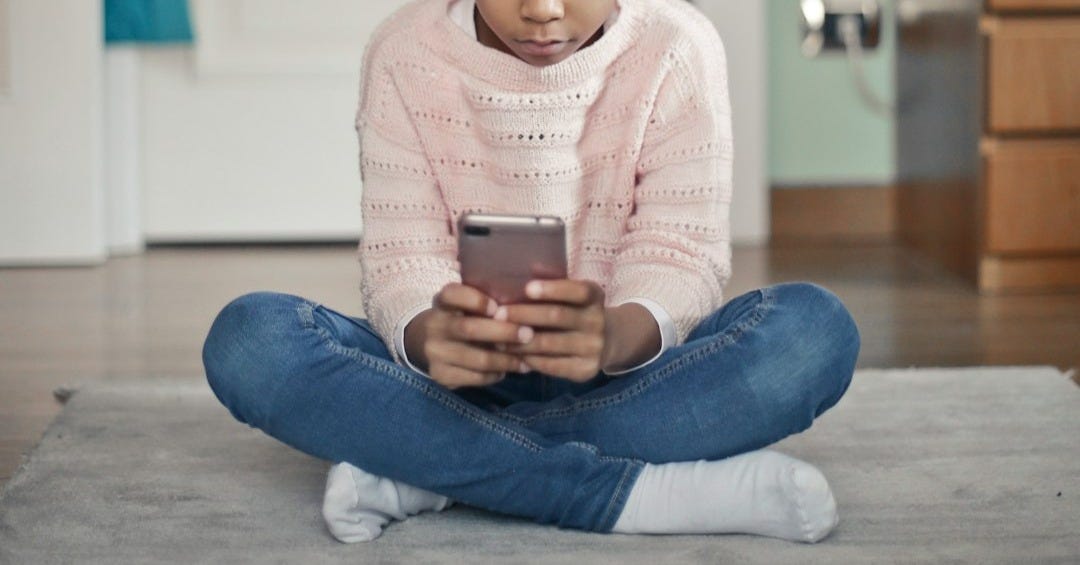 girl in white sweater and blue denim jeans sitting on floor