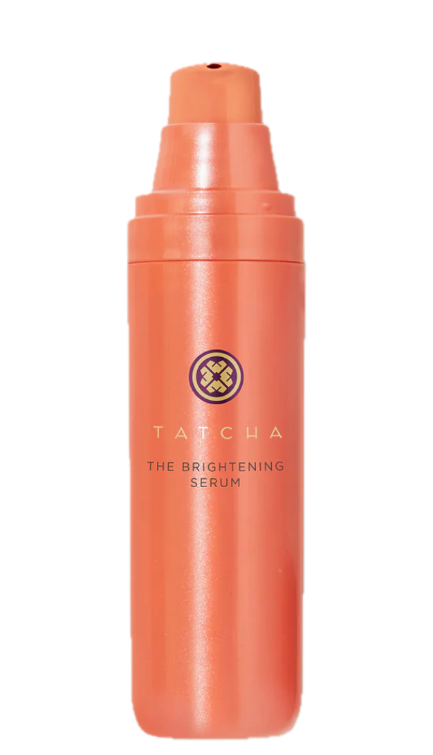 A high-resolution shot of the Tatcha Violet-C Brightening Serum in its tall, vibrant orange pump bottle. The image captures the luxury packaging and material quality that Donna Francis evaluates with her editorial "BS detector".