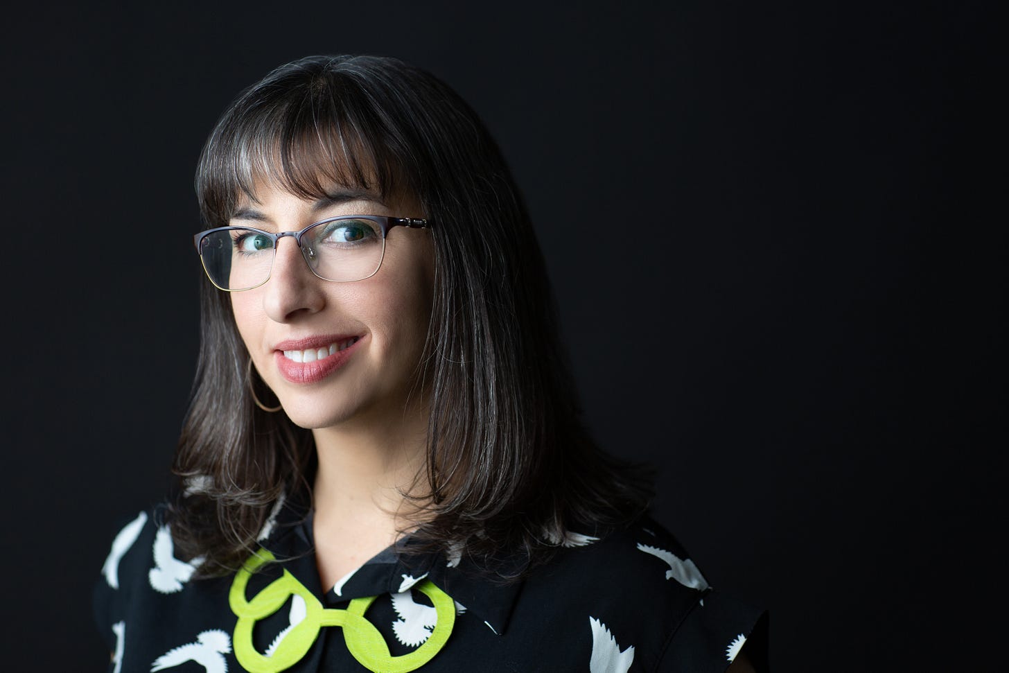 Photo of brown-haired female rabbi with bangs, glasses, wry smile