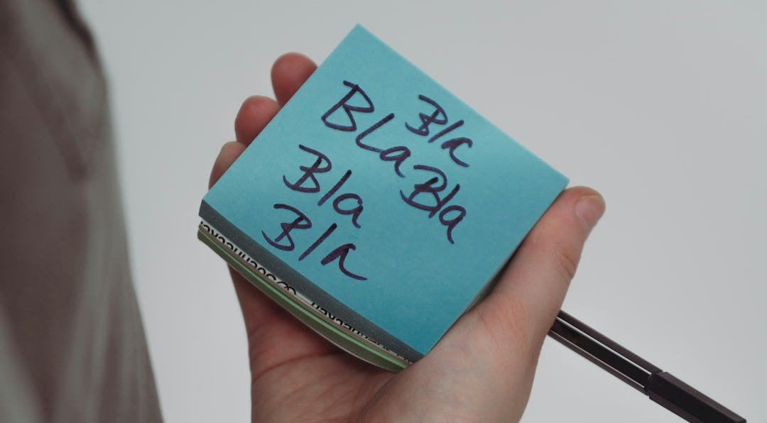 A person holding a pen and a sticky note A person holding a pen and a sticky note
