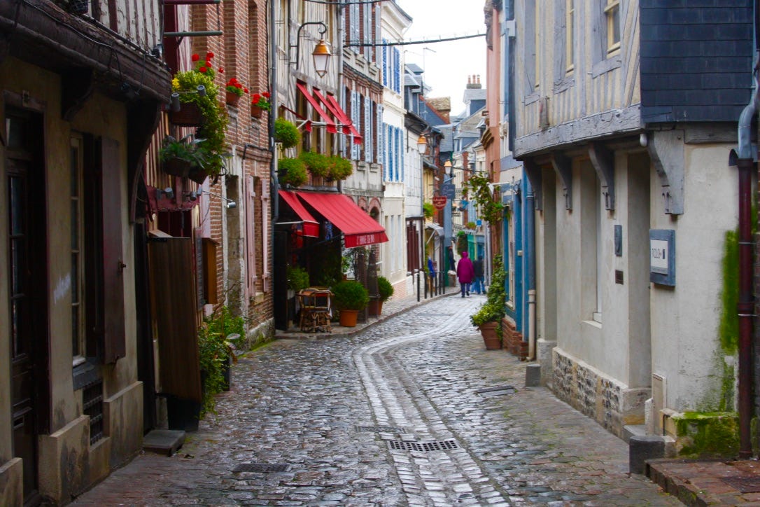 A cobblestone street with buildings and people walking

AI-generated content may be incorrect.