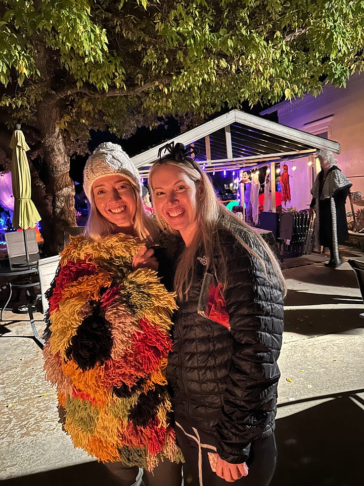 Author and author friend in costume at an outdoor party. Plus, author wearing yarn coat by a Christmas tree.