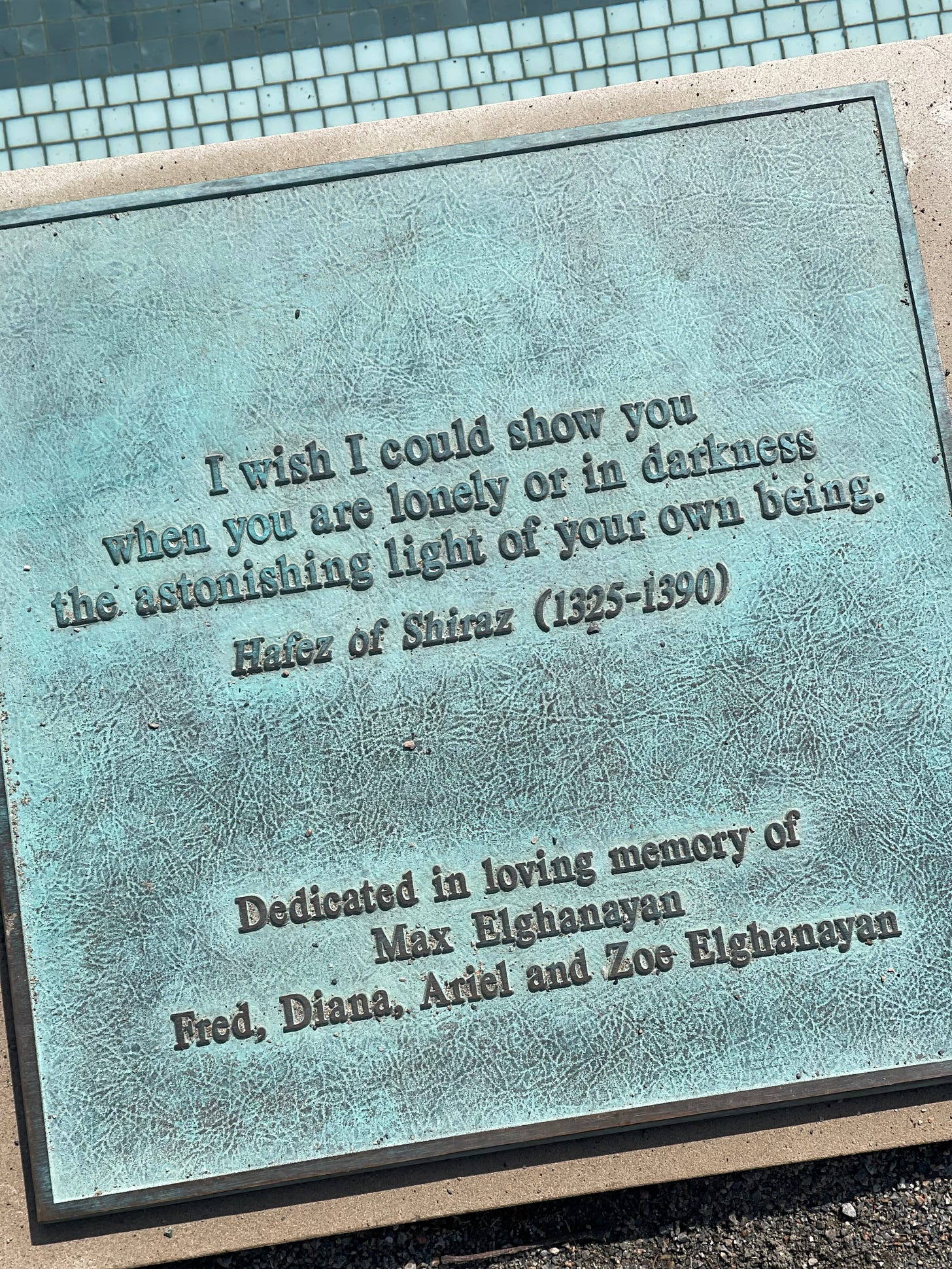 A placard mounted next to a wading pool with a quote on it A placard mounted next to a wading pool with a quote on it