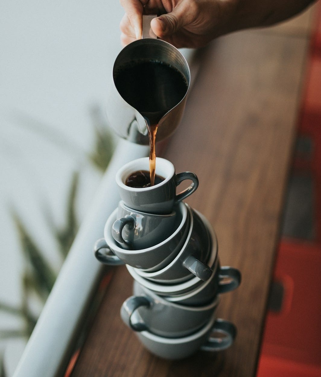 person holding gray stainless steel pitcher bside window