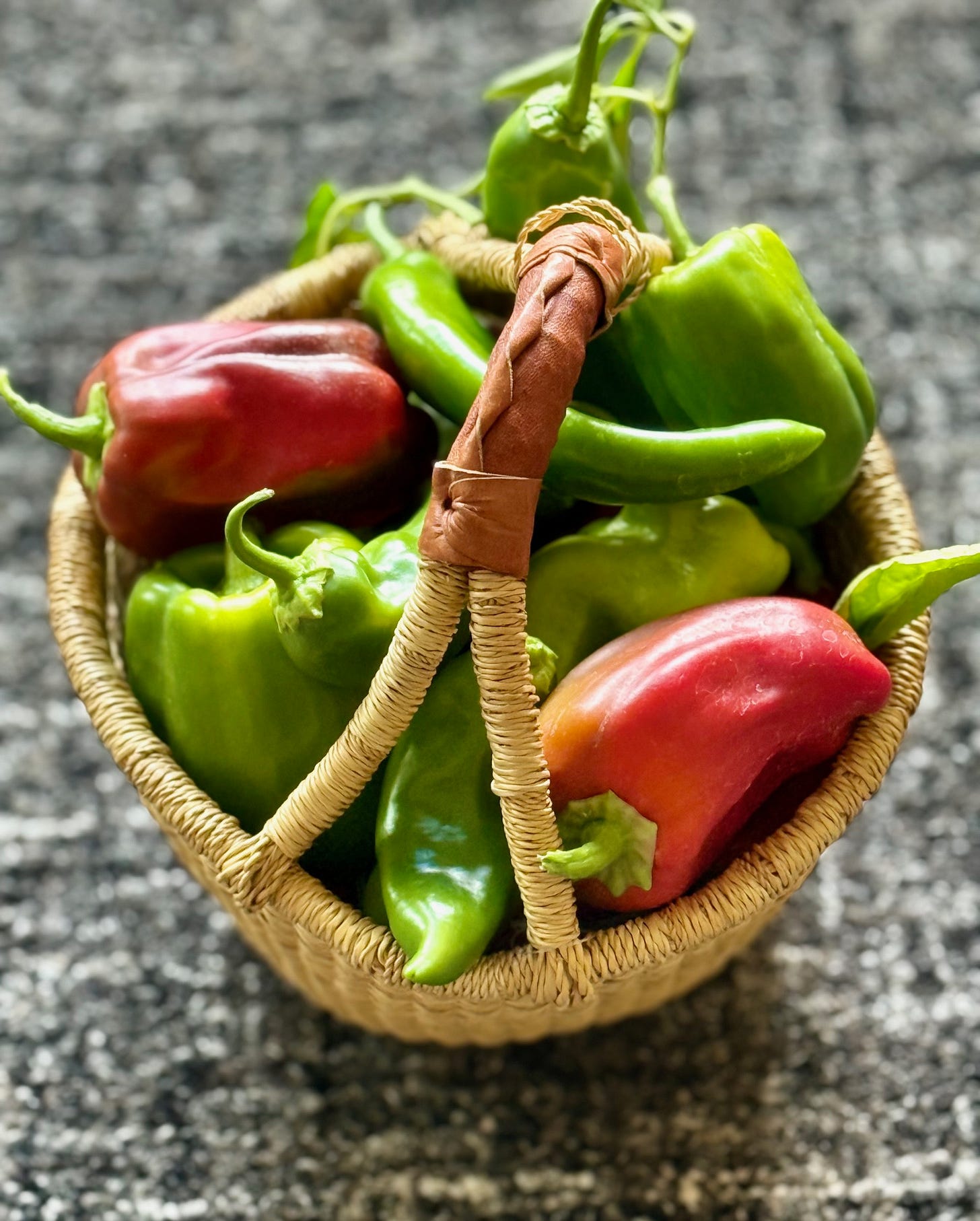 A basket of green and red peppers. 