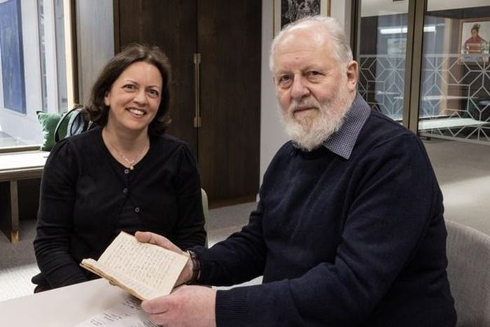 image depicts two people, one holding a Tudor-era manuscript image depicts two people, one holding a Tudor-era manuscript