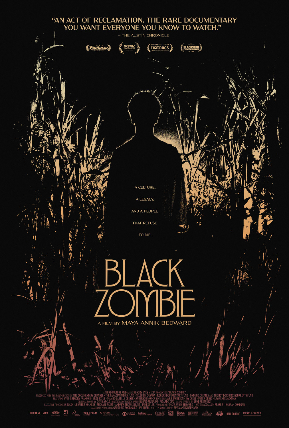 Film poster for Black Zombie, a documentary directed by Maya Annik Bedward. Against a nearly black background, a silhouetted figure stands surrounded by dense, towering vegetation illuminated in muted gold and reddish tones. Gold lettering reads, “A culture, a legacy, and a people that refuse to die.” At the top, a review from The Austin Chronicle describes the film as “An act of reclamation,” alongside festival laurels from Fantasia, SXSW, Hot Docs, and BlackStar Film Festival 2026. The title Black Zombie appears prominently in large gold letters near the bottom. Film poster for Black Zombie, a documentary directed by Maya Annik Bedward. Against a nearly black background, a silhouetted figure stands surrounded by dense, towering vegetation illuminated in muted gold and reddish tones. Gold lettering reads, “A culture, a legacy, and a people that refuse to die.” At the top, a review from The Austin Chronicle describes the film as “An act of reclamation,” alongside festival laurels from Fantasia, SXSW, Hot Docs, and BlackStar Film Festival 2026. The title Black Zombie appears prominently in large gold letters near the bottom.