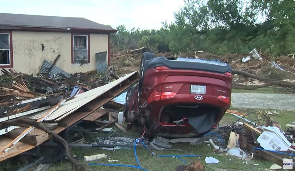 video screenshot showing a battered house, its yard full of wreckage, including an overturned red car, debris from a house or mobile home, and an air conditioner. video screenshot showing a battered house, its yard full of wreckage, including an overturned red car, debris from a house or mobile home, and an air conditioner.