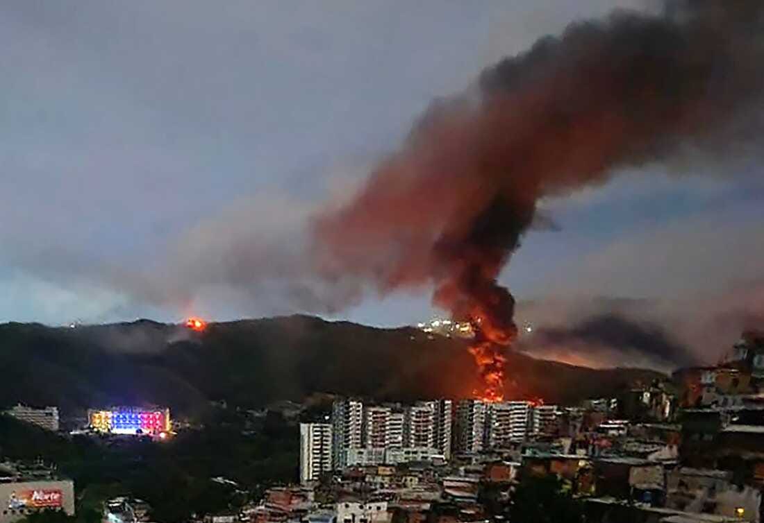 Fire at Fuerte Tiuna, Venezuela's largest military complex, is seen from a distance after a series of explosions in Caracas on January 3, 2026.