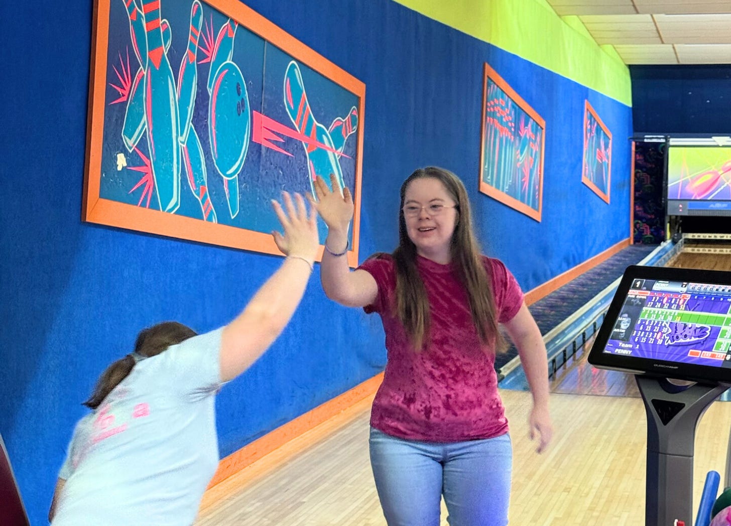 Penny giving her friend a high five at the bowling alley