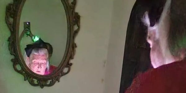 photo shows a woman reflected in a mirror in a poorly lit room