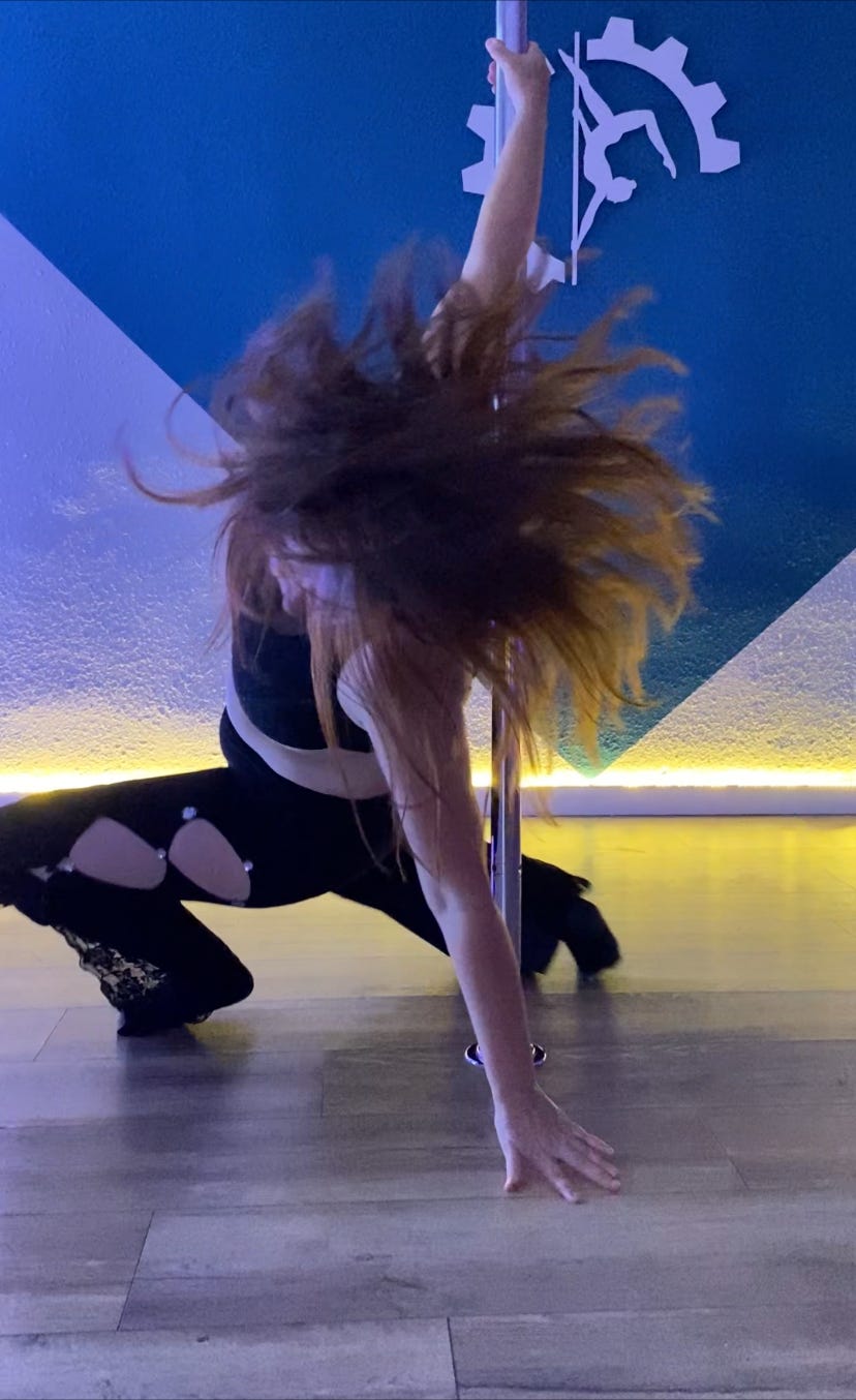 Woman performing pole dance choreography with hair in motion at age 46, demonstrating artistic movement and flow in midlife pole fitness. Woman performing pole dance choreography with hair in motion at age 46, demonstrating artistic movement and flow in midlife pole fitness.