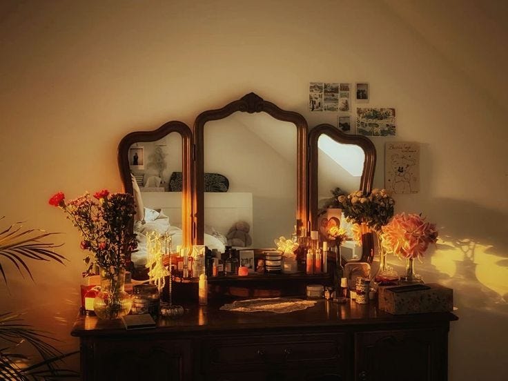 This may contain: a dresser with flowers and candles on it in front of a mirror that is lit up