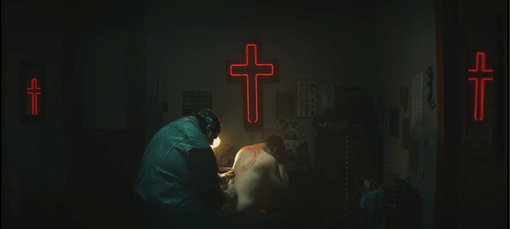 A scene from Wildcat (2023) where Rafael Casal portrays O.E. Parker getting a back tat. A scene from Wildcat (2023) where Rafael Casal portrays O.E. Parker getting a back tat.
