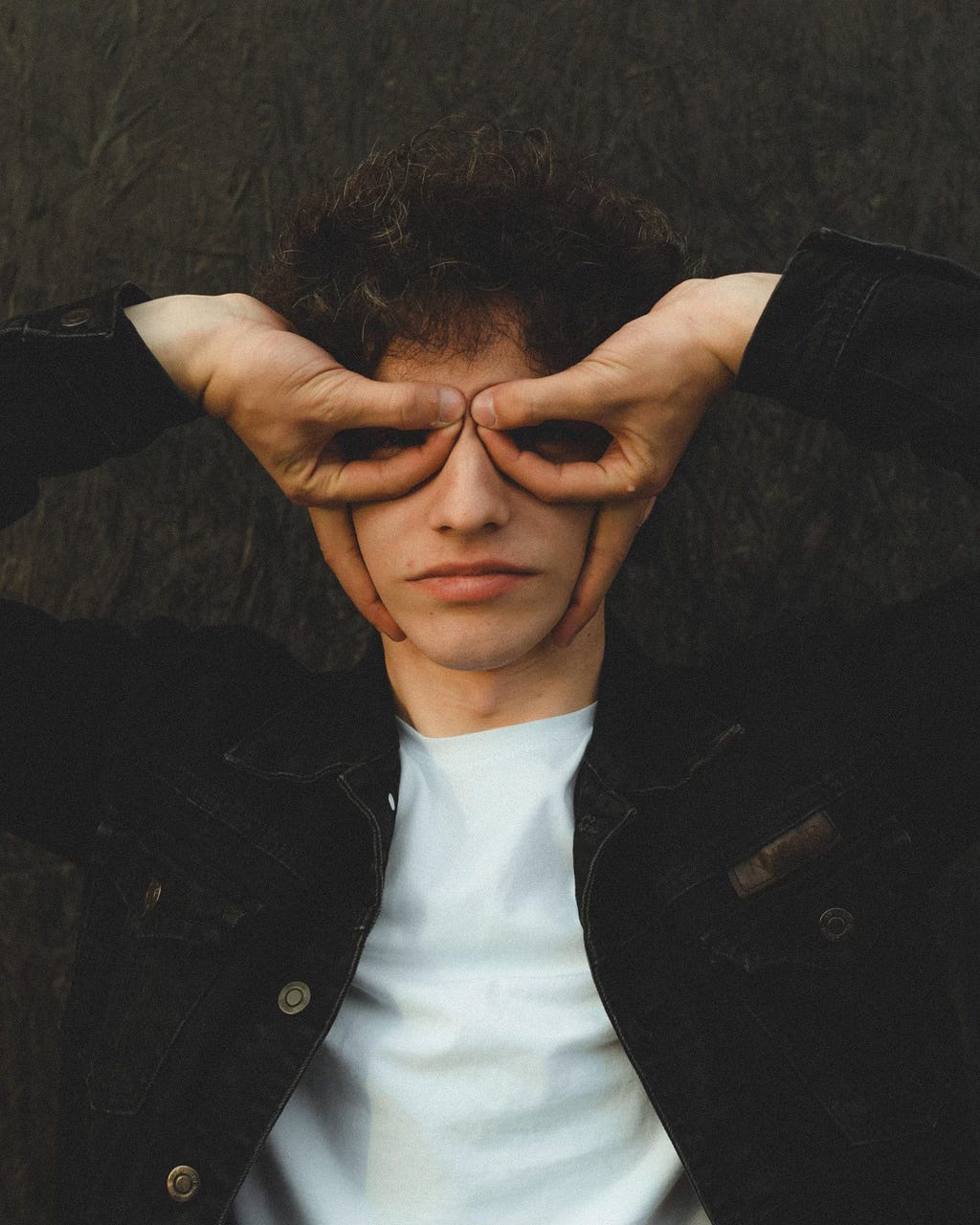 photo of a young adult making that hilarious upside-down mask with his hands over his eyes, like a dorky superhero