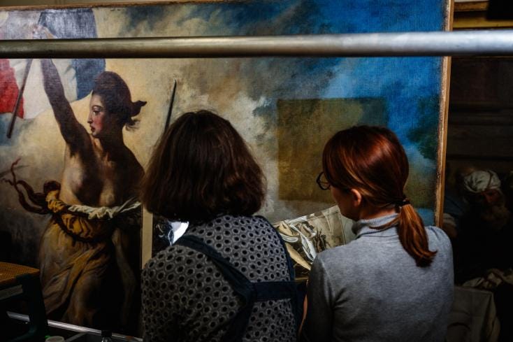 Des restaurateurs travaillent sur le tableau "La liberté guidant le peuple" d'Eugène Delacroix, dans un laboratoire du Musée du Louvre à Paris, le 28 février 2024