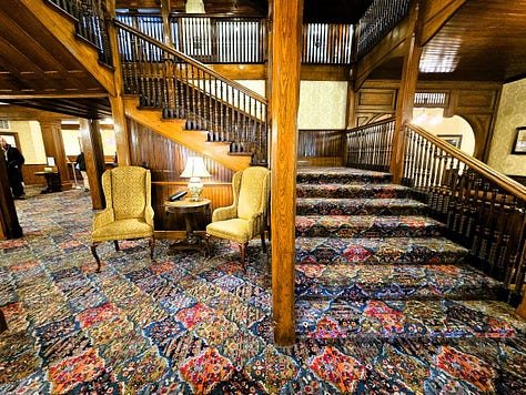 The historic central staircase at Mohonk with wooden spindles and colorful carpet.