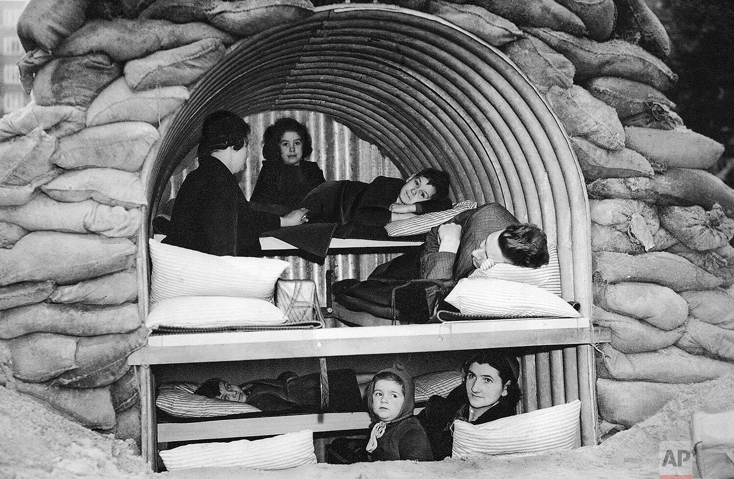 A London family demonstrates ingenious adaptation, transforming a small Anderson shelter into a compact family dwelling, complete with bunks for eight, during prolonged air raid alarms on Oct. 19, 1940, showcasing resilience during the Blitz. A London family demonstrates ingenious adaptation, transforming a small Anderson shelter into a compact family dwelling, complete with bunks for eight, during prolonged air raid alarms on Oct. 19, 1940, showcasing resilience during the Blitz.