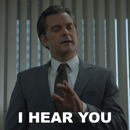 a man in a suit and tie has his eyes closed and says i hear you