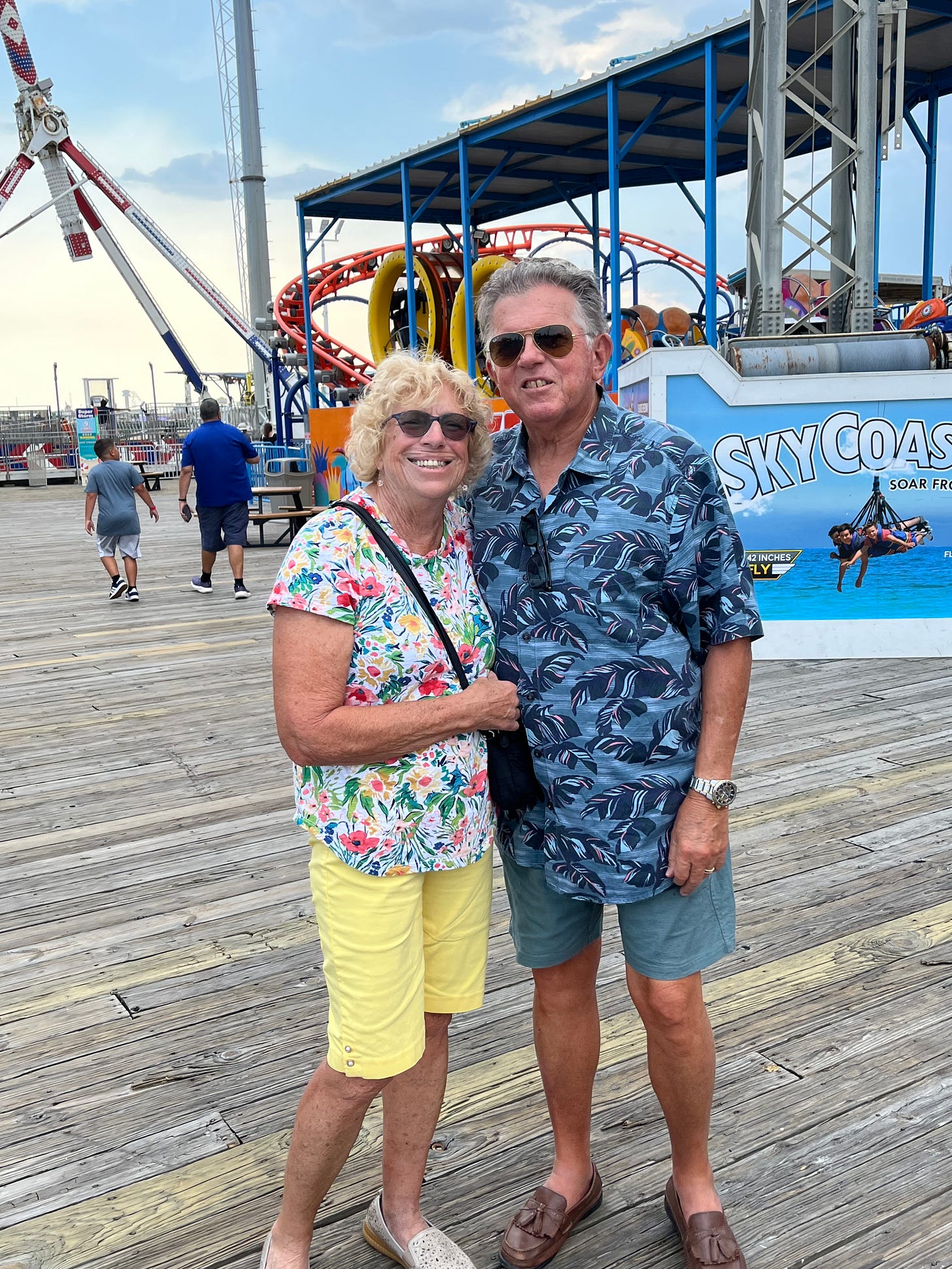 My parents standing in front of some amusement rides.