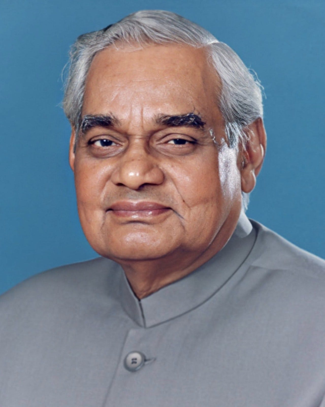 Official portrait of Atal Bihari Vajpayee in a grey collarless jacket against a blue background