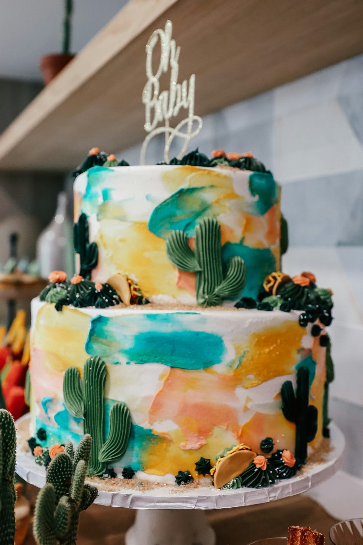 two-tiered cake with cactus decorations and an 'Oh Baby' topper