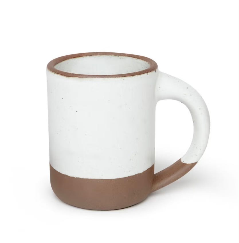 Handmade ceramic mug with a white glazed upper half and unglazed clay bottom, featuring a rounded handle Handmade ceramic mug with a white glazed upper half and unglazed clay bottom, featuring a rounded handle