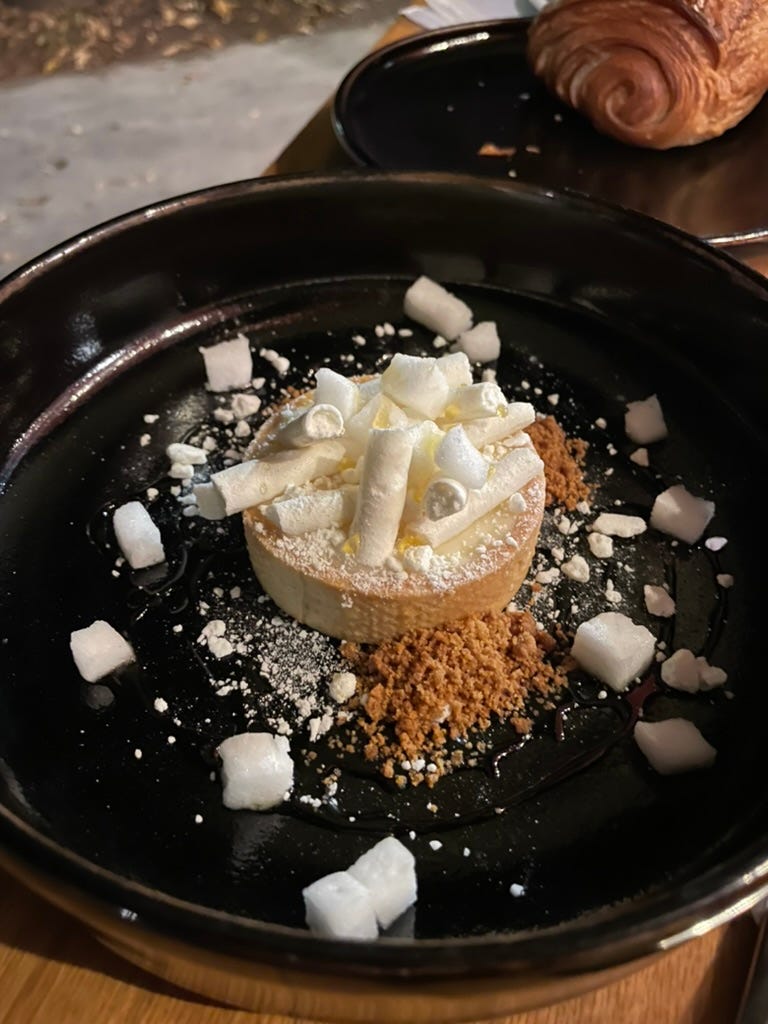 A lemon tart on a black plate.