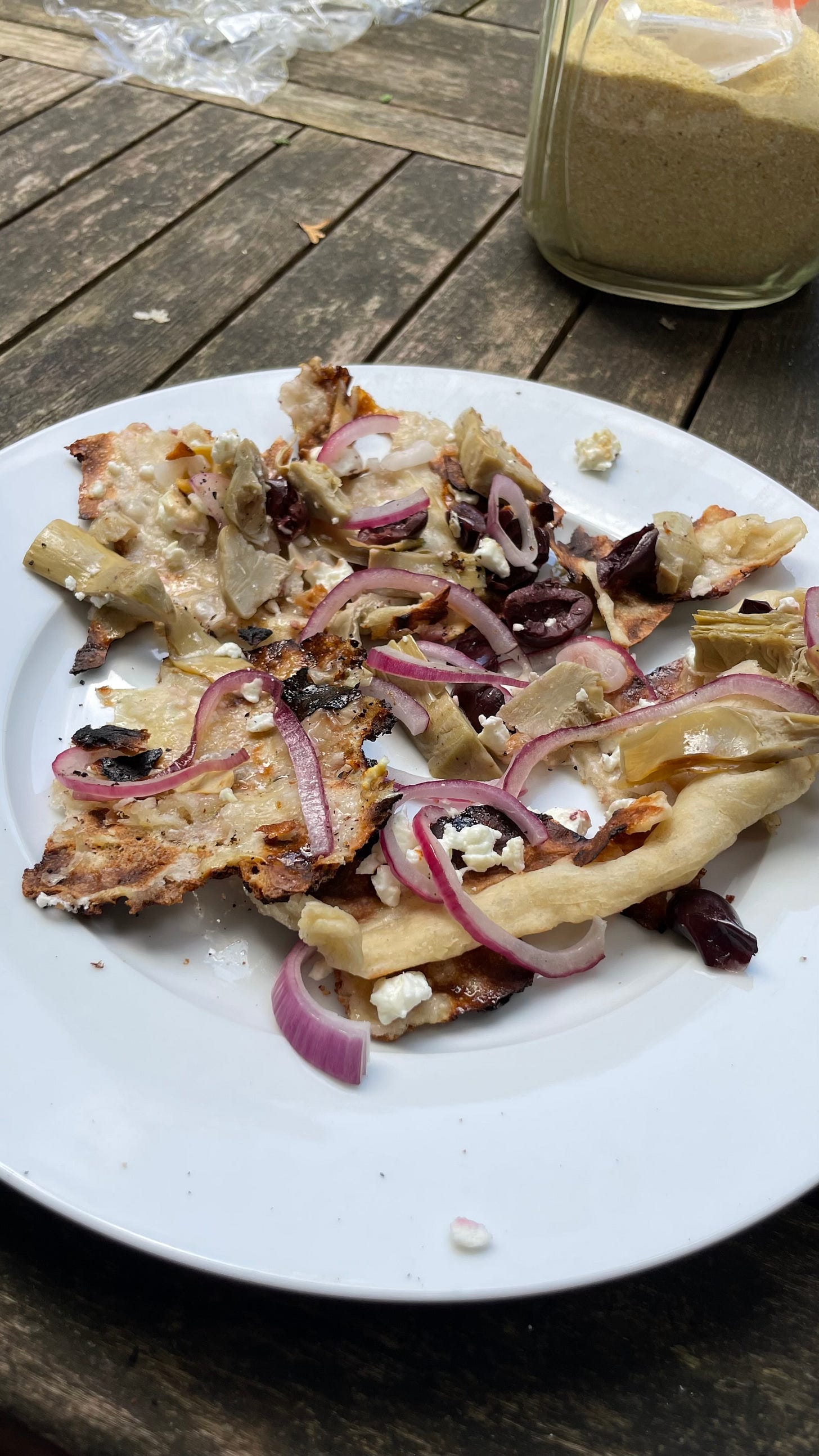 A plate of pieces of grilled pizza dough and toppings that have been scraped off the pan. It is a mess. A plate of pieces of grilled pizza dough and toppings that have been scraped off the pan. It is a mess.
