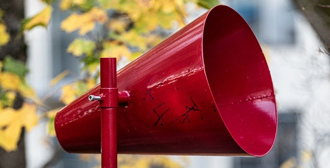 A red mailbox sitting next to a tree